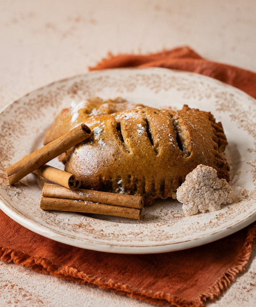 Pumpkin Cheesecake Hand Pie on a plate with cinnamon sticks